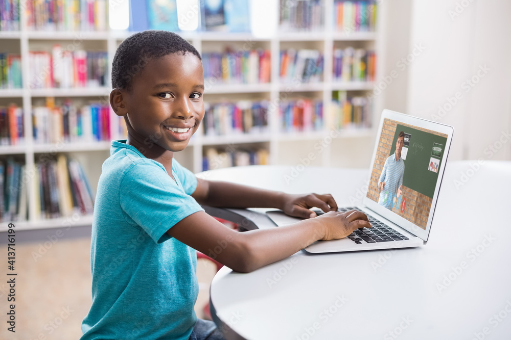 Portrait of male african american student having a video call with male teacher on laptop at library