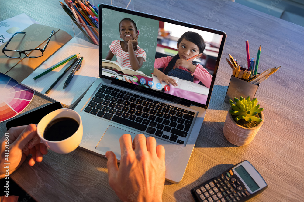 Mid section of teacher having a video conference with two female students on laptop at school