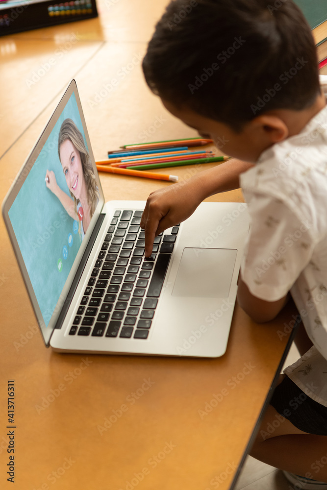 Male student having a video call with female teacher on laptop at school