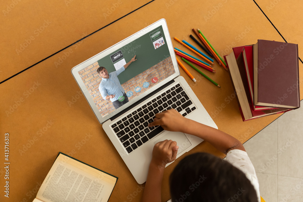 Overhead view of male student having a video call with male teacher on laptop at school