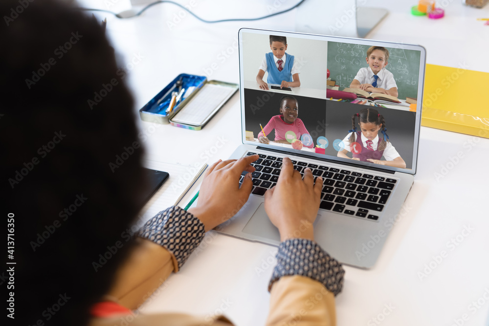 Female teacher having a video conference with multiple students on laptop at school