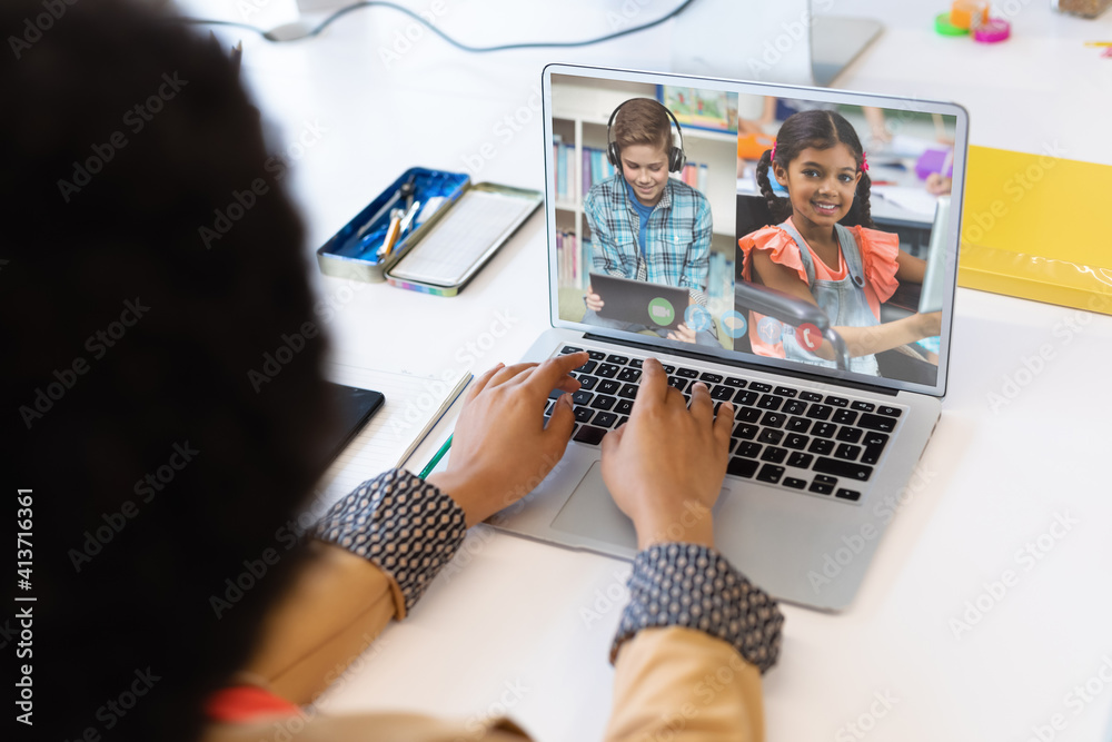 Female teacher having a video conference with male and female students on laptop at school