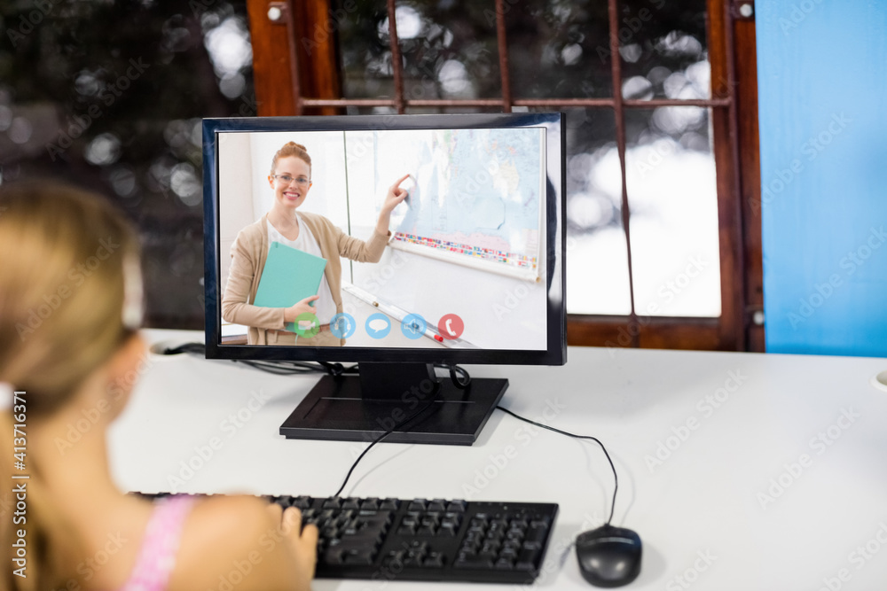 Female student having a video call with female teacher on computer at school