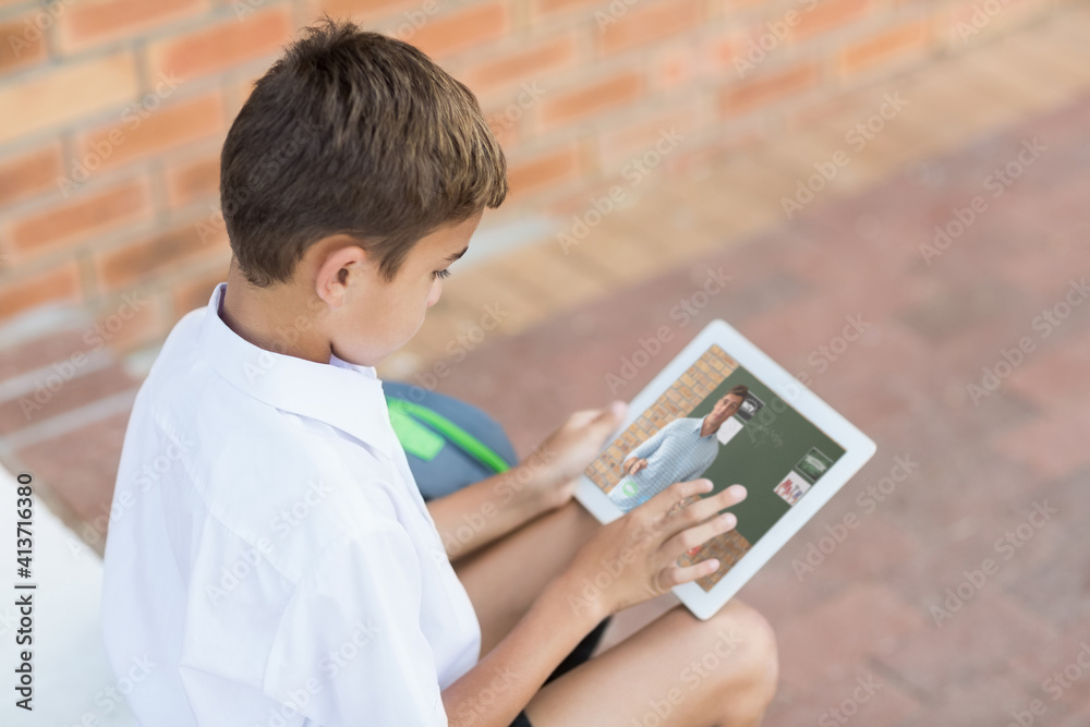 Male caucasian student having a video call with male teacher on digital tablet at school