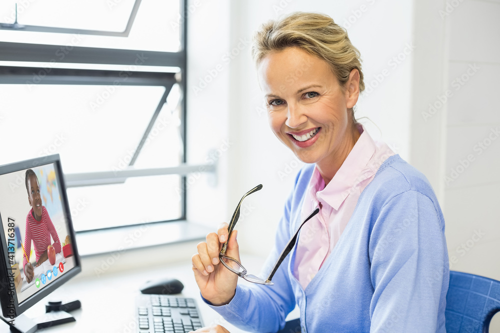 Portrait of female caucasian teacher having a video call with female student on computer at school