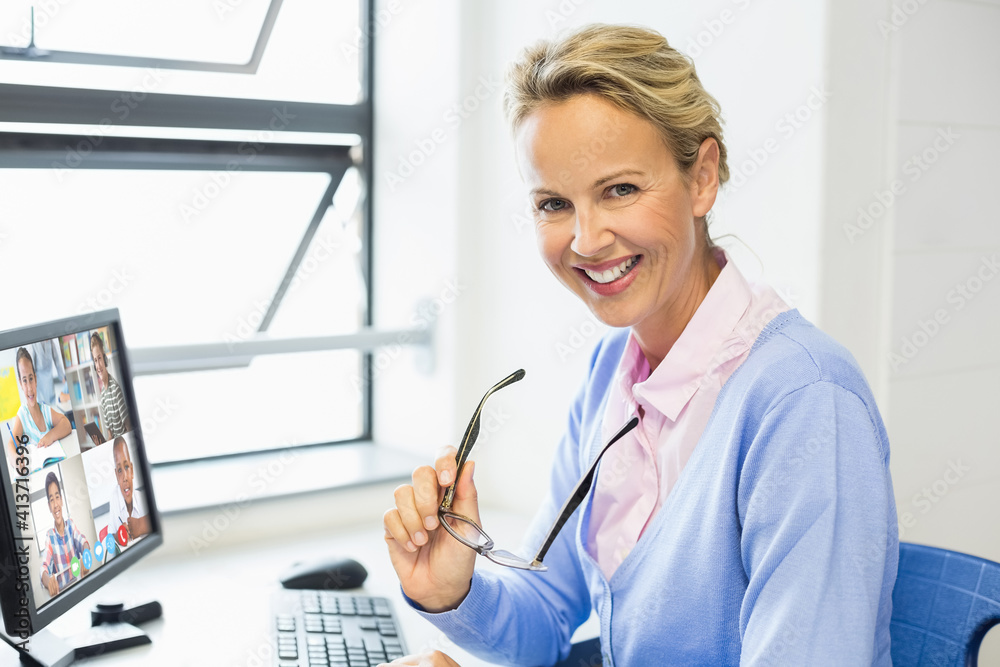 Portrait of female caucasian teacher having a video conference with multiple students on computer at