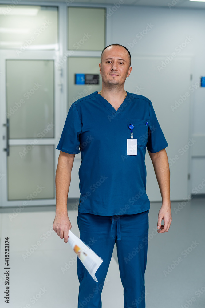 Portrait of mature male doctor standing in hospital corridor. Healthcare And Medicine.