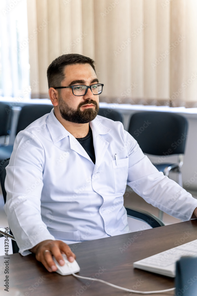 Doctor typing and using his computer in the office