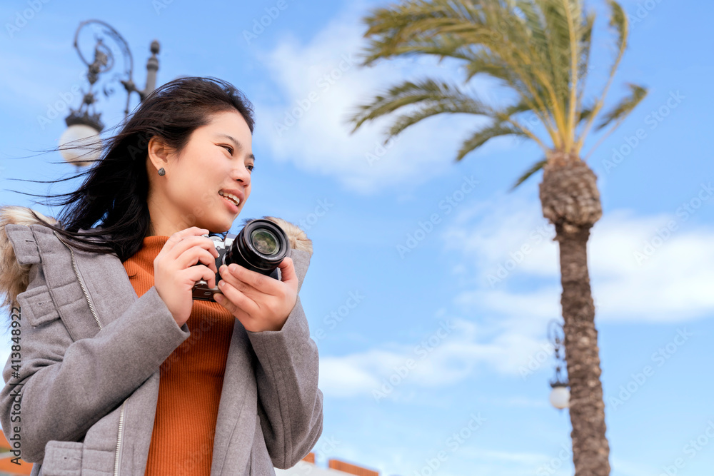 迷人的亚洲女性旅行者旅游手用相机观光海滩蓝天和棕榈树i