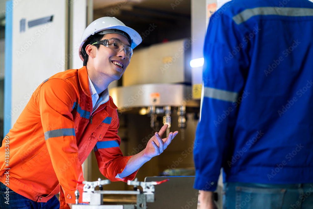 Male Asian engineer professional  having a discussion standing concult cnc machine in the factory ,t