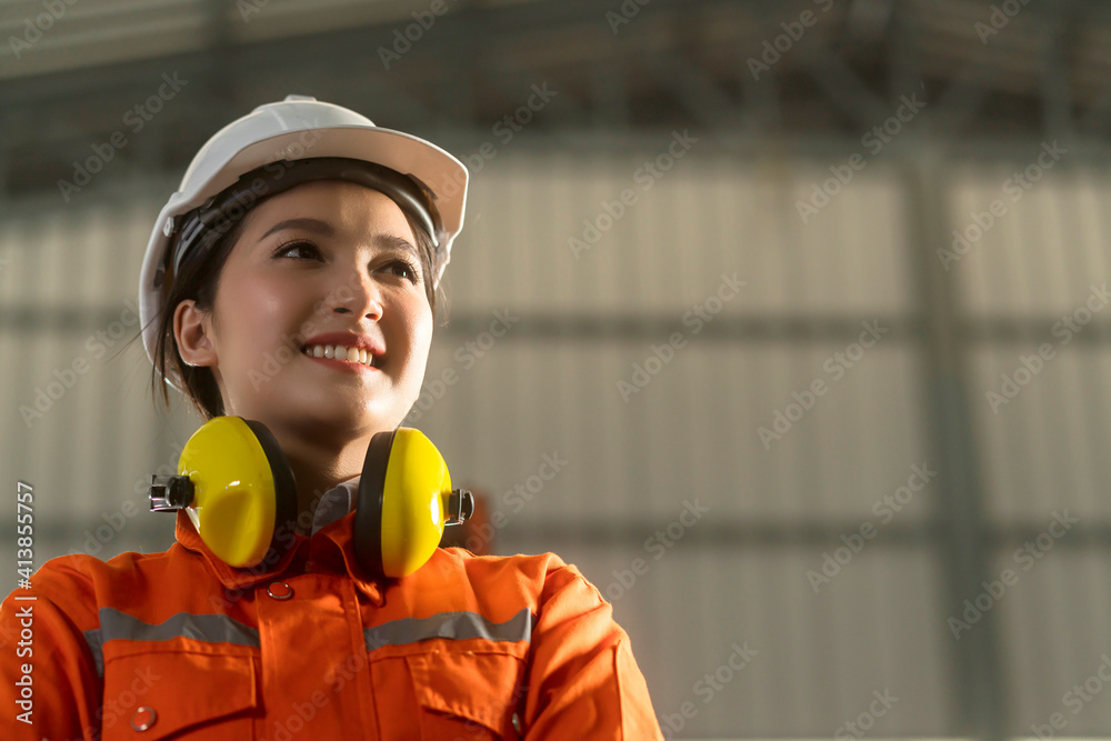 portrait of asian female engineer wearing uniform and saftey helmet standing confident and cheerful 