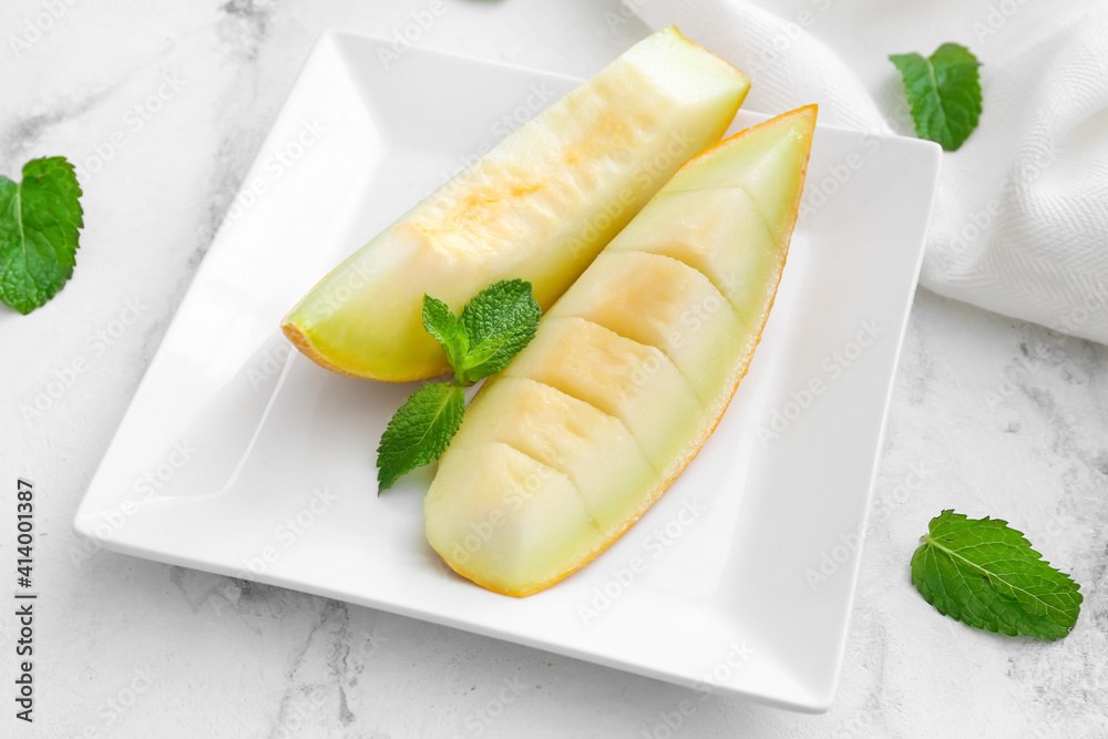 Plate with sweet cut melon on light background