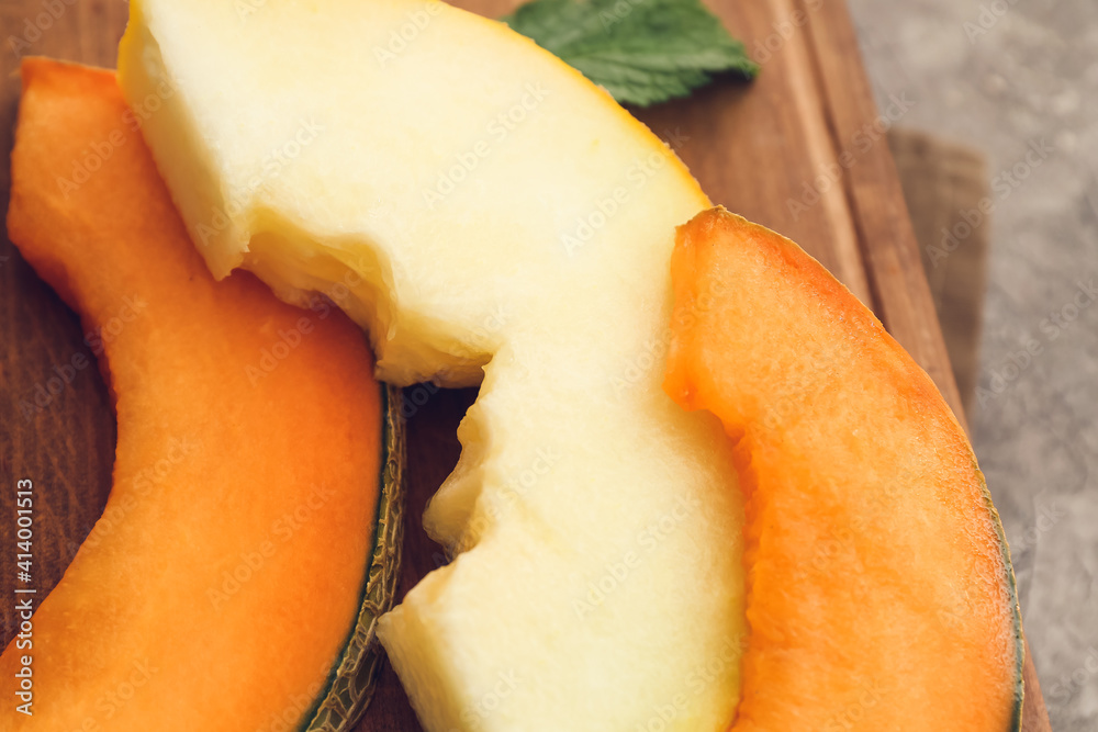 Board with sweet cut melon on gray background, closeup