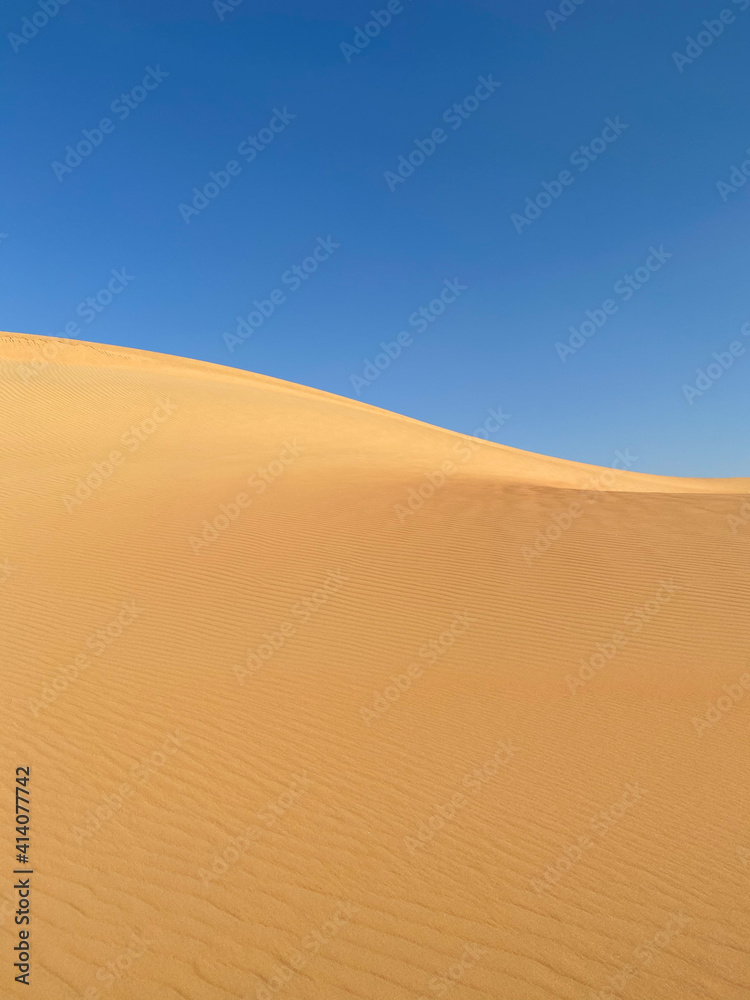 Simple abstract desert scenery with sand dunes and blue sky. Liwa desert, Abu Dhabi, UAE.