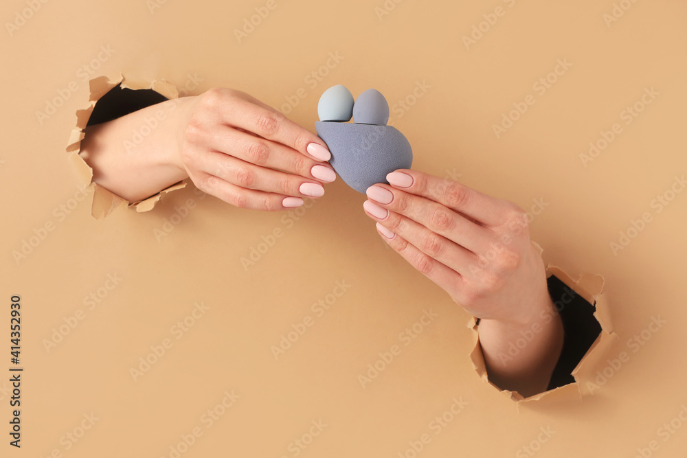 Hands with makeup sponges visible through holes in color paper