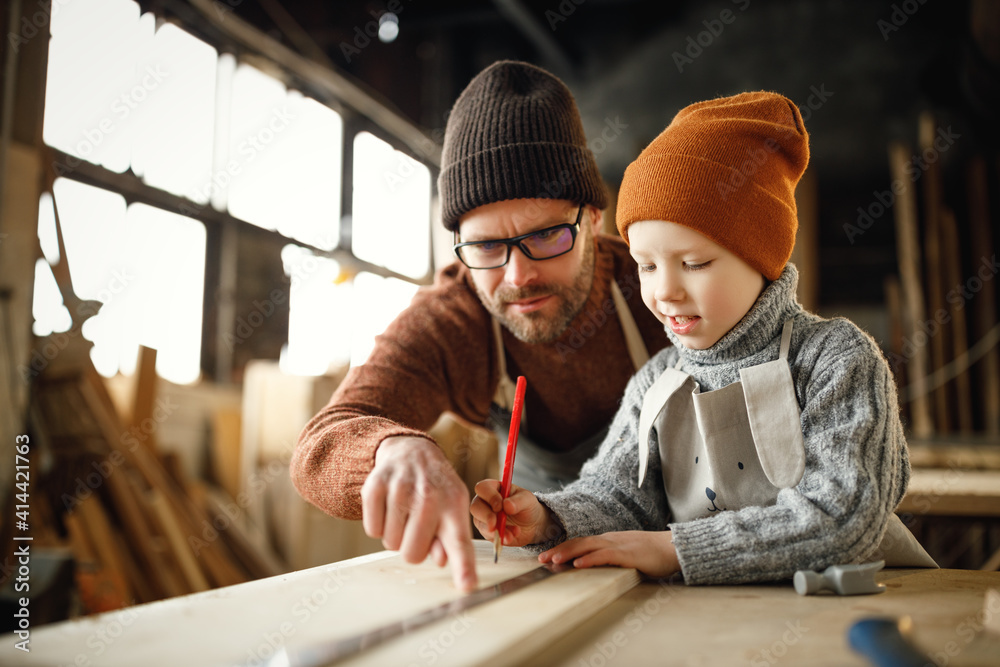 Little boy with father creating woodwork in workshop