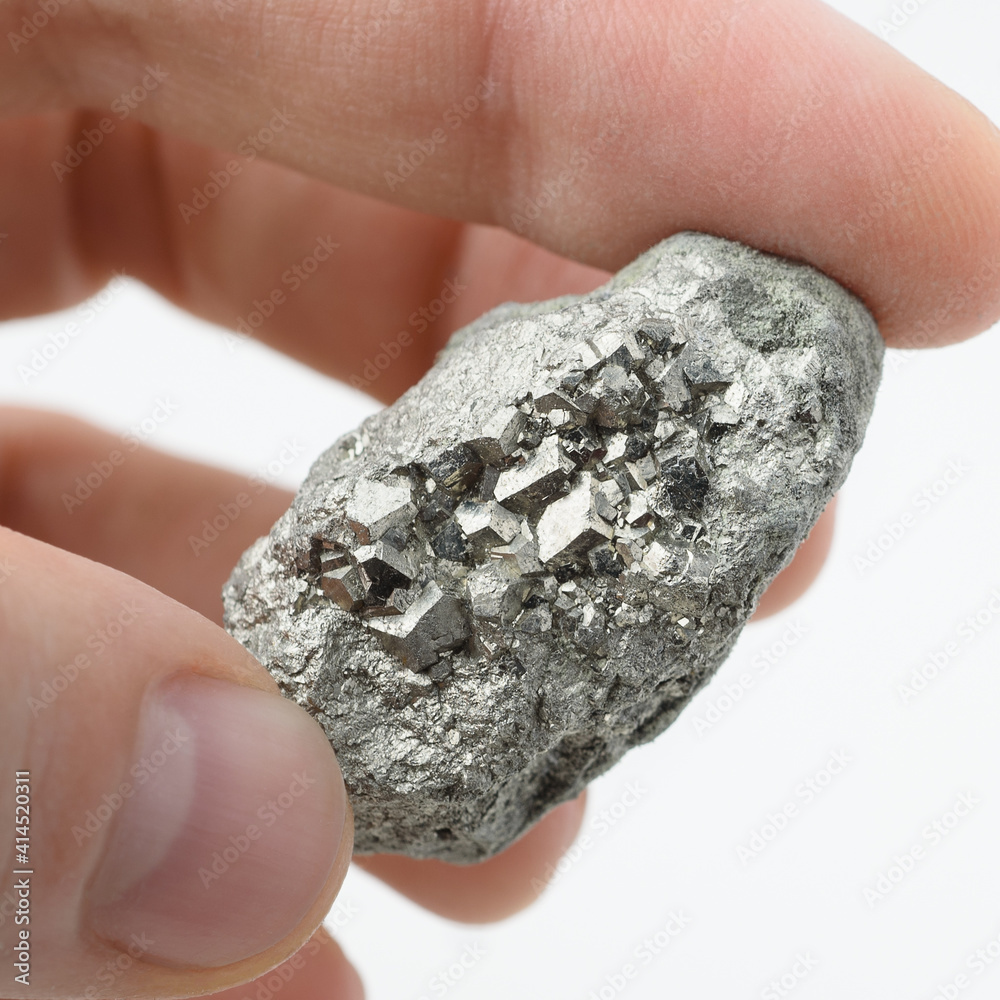 Nugget of pyrite in hand, closeup shot. Natural mineral ore isolated on white background