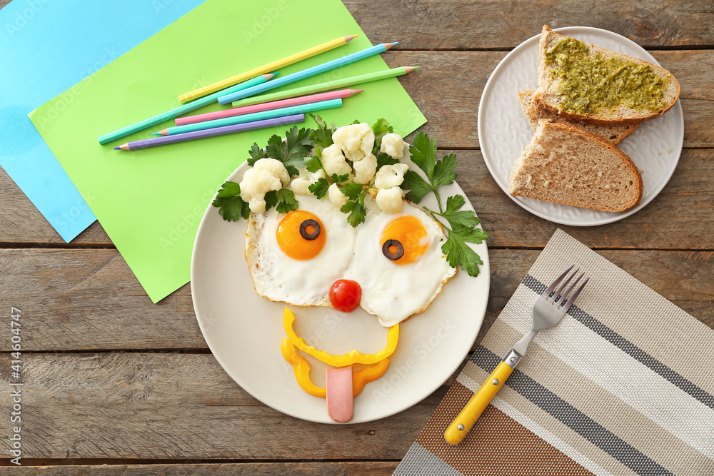 Creative breakfast for children with eggs, fresh vegetables and toasts on wooden background