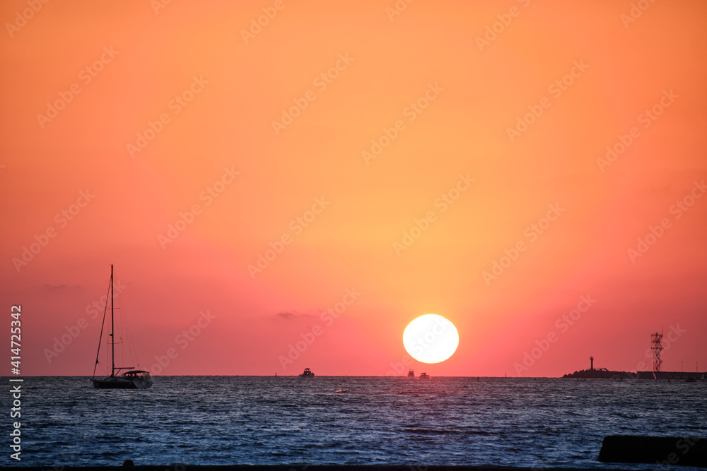 壮观的海上日落，太阳仍在水面上。背景是红色、橙色的日落