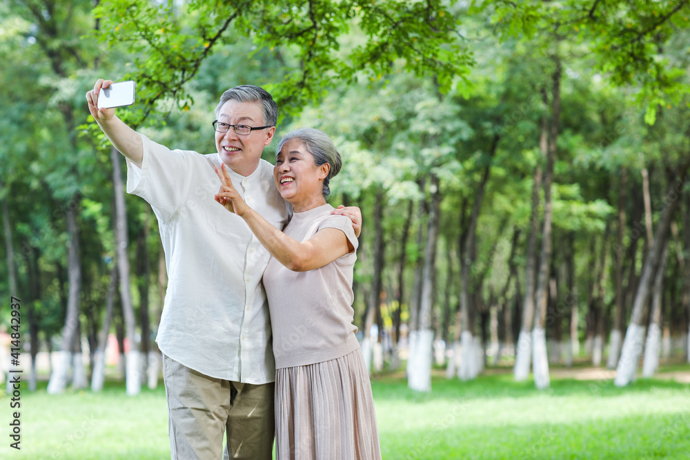 幸福的老夫妻在公园用手机自拍