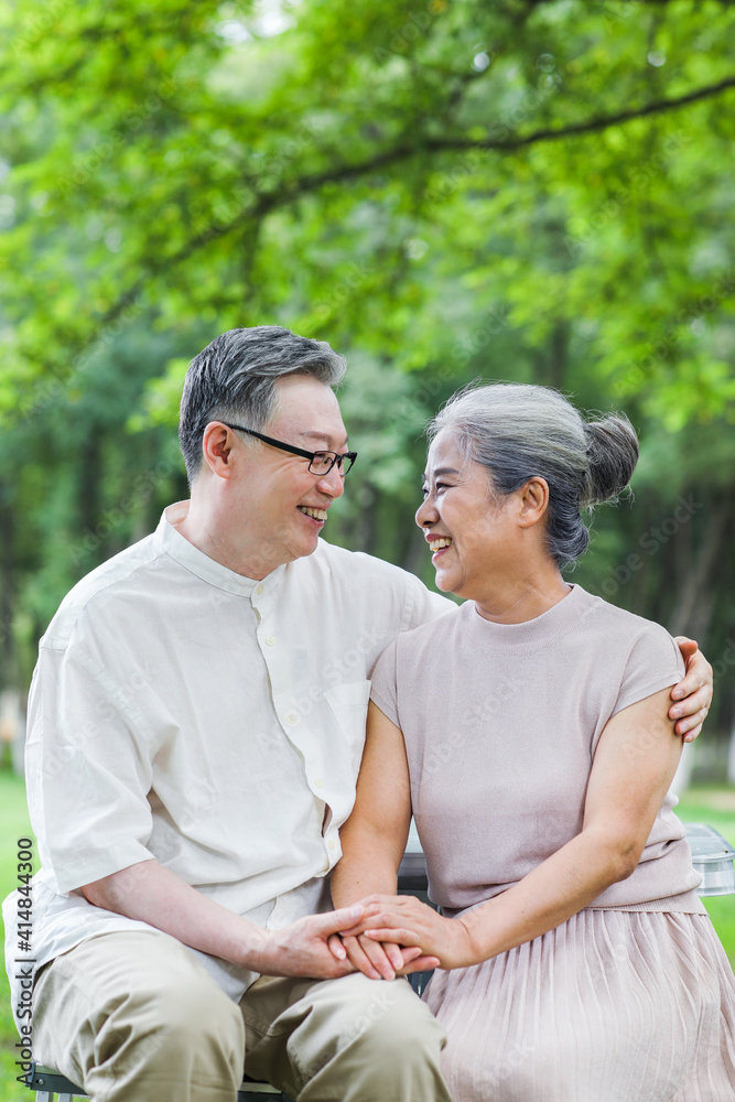 快乐的老夫妇坐在户外公园的椅子上