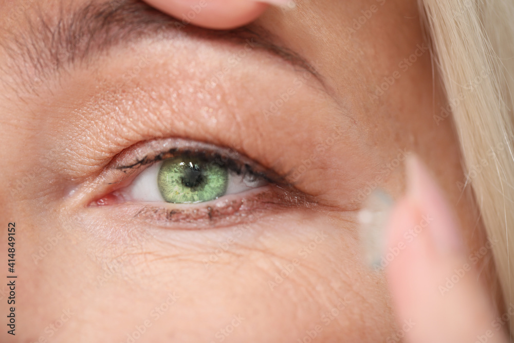 Mature woman putting in contact lenses, closeup