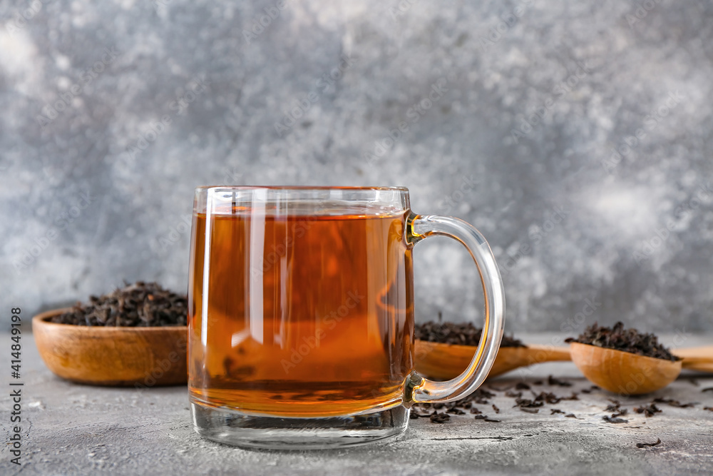 Cup of tea and dry leaves on dark background