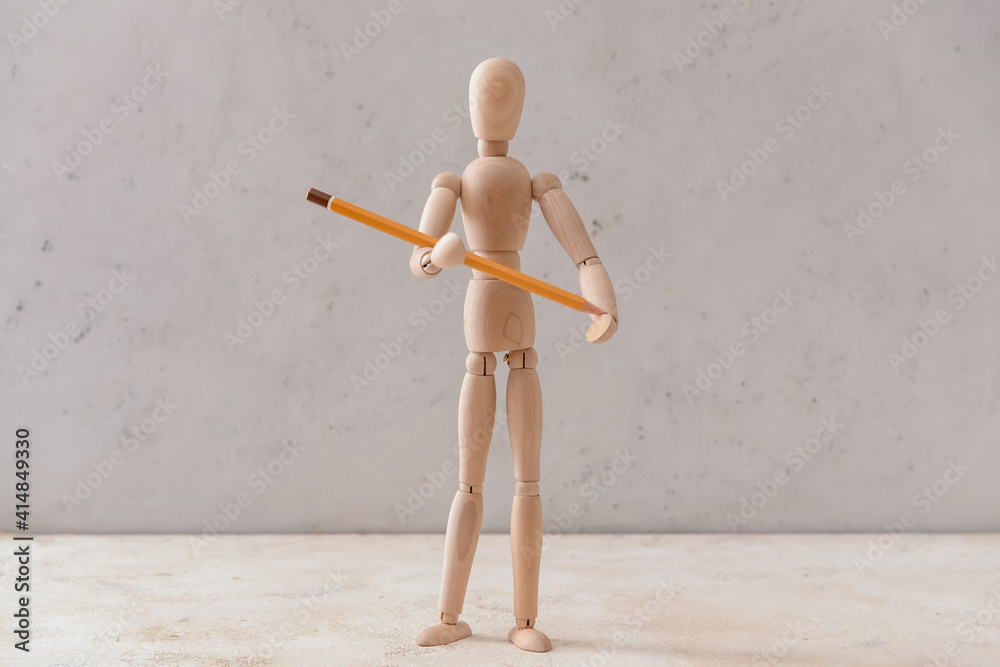 Wooden mannequin with pencil on light background