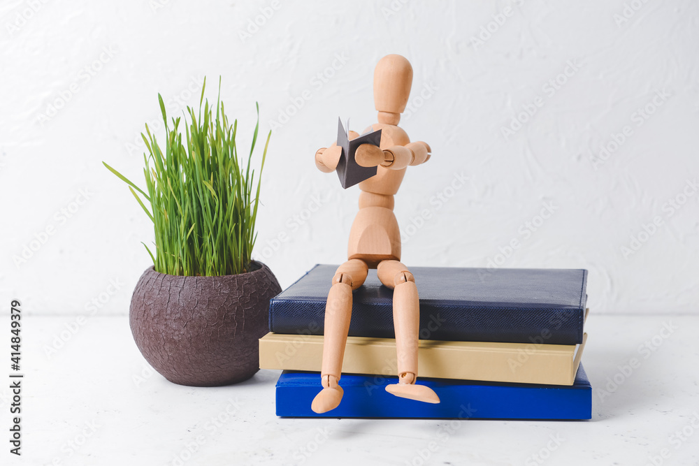 Wooden mannequin with books on light background