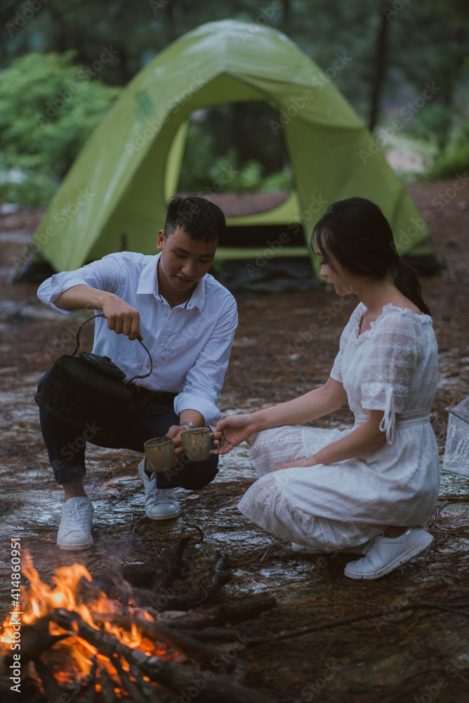 一对年轻的亚洲夫妇坐在篝火旁