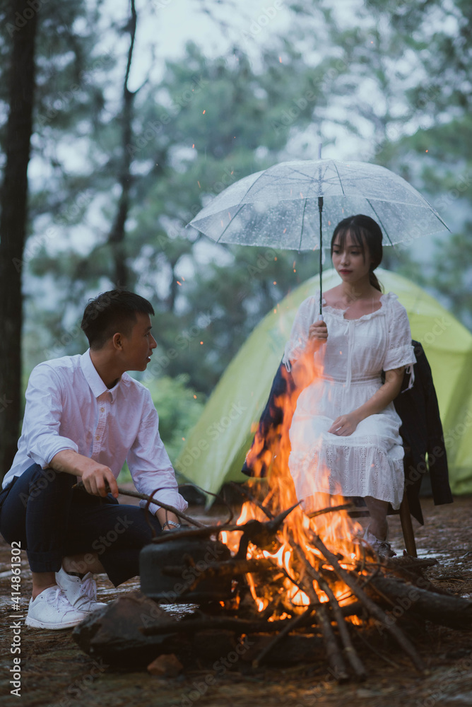 一对年轻的亚洲夫妇坐在篝火旁