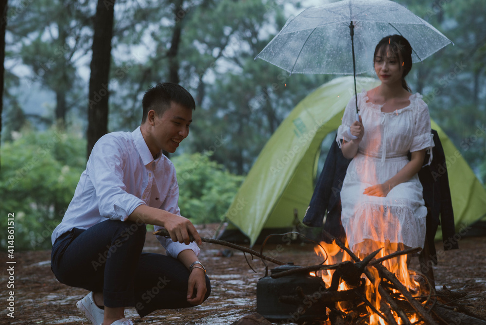 Young Asian couple sitting together by a campfire
