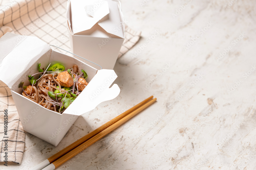 Container with tasty soba noodles and meat on light background