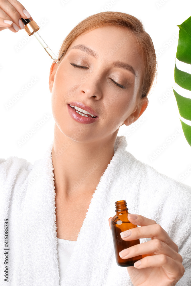 Beautiful young woman with cosmetic product and tropical leaf on white background