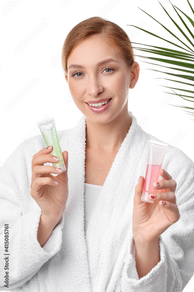 Beautiful young woman with cosmetic products and tropical leaf on white background, closeup