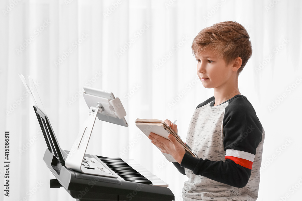 Little boy taking music lessons online at home