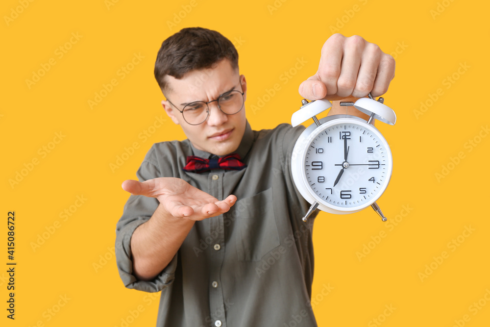 Stressed teenager with alarm clock on color background