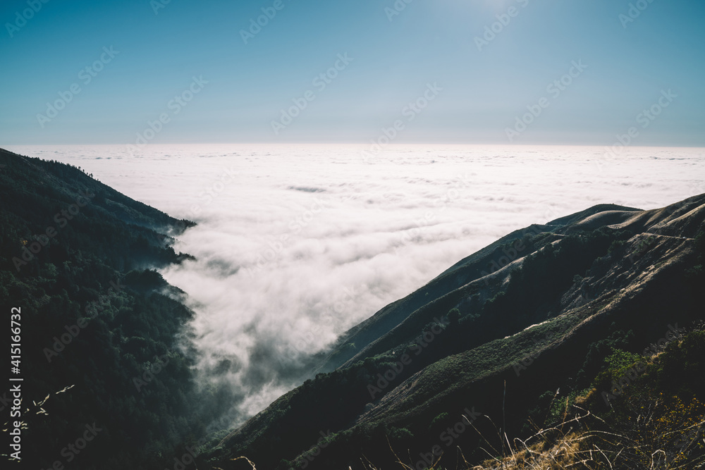 Mountainous terrain in  dense clouds with shining sun