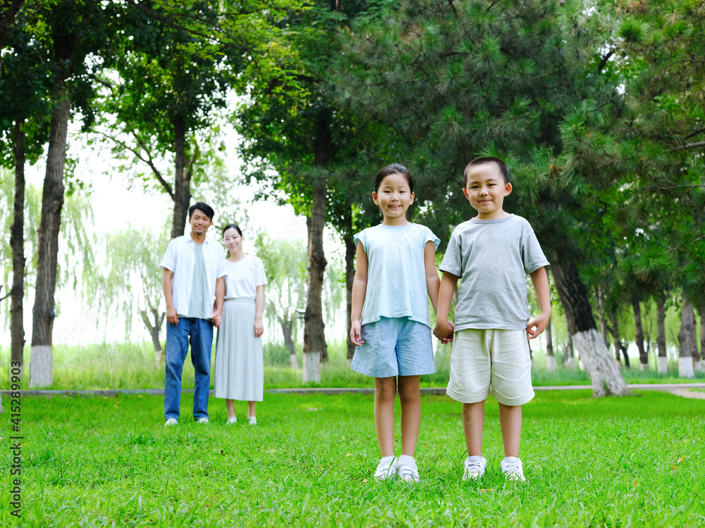 Happy family of four playing in the park