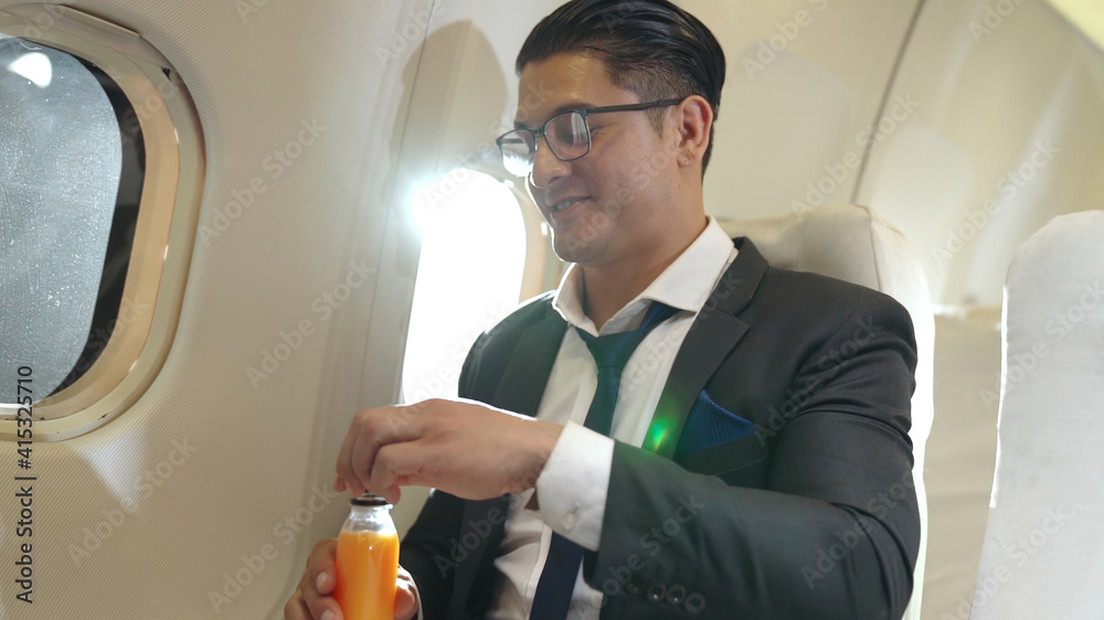 Businessman have orange juice served by an air hostess in airplane . Business trip travel concept .