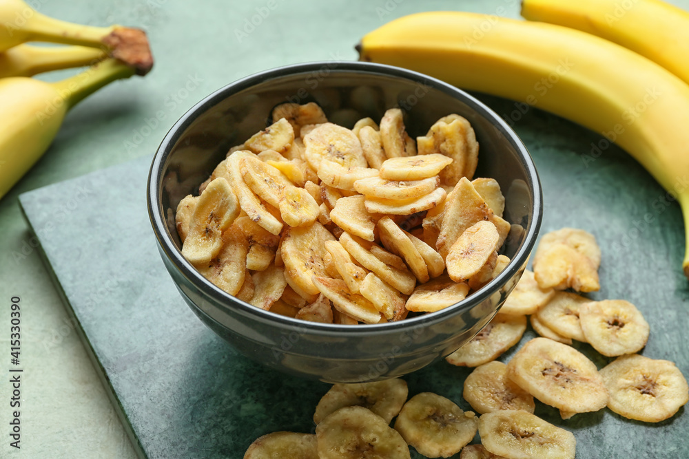 Fresh bananas and crispy chips on color background