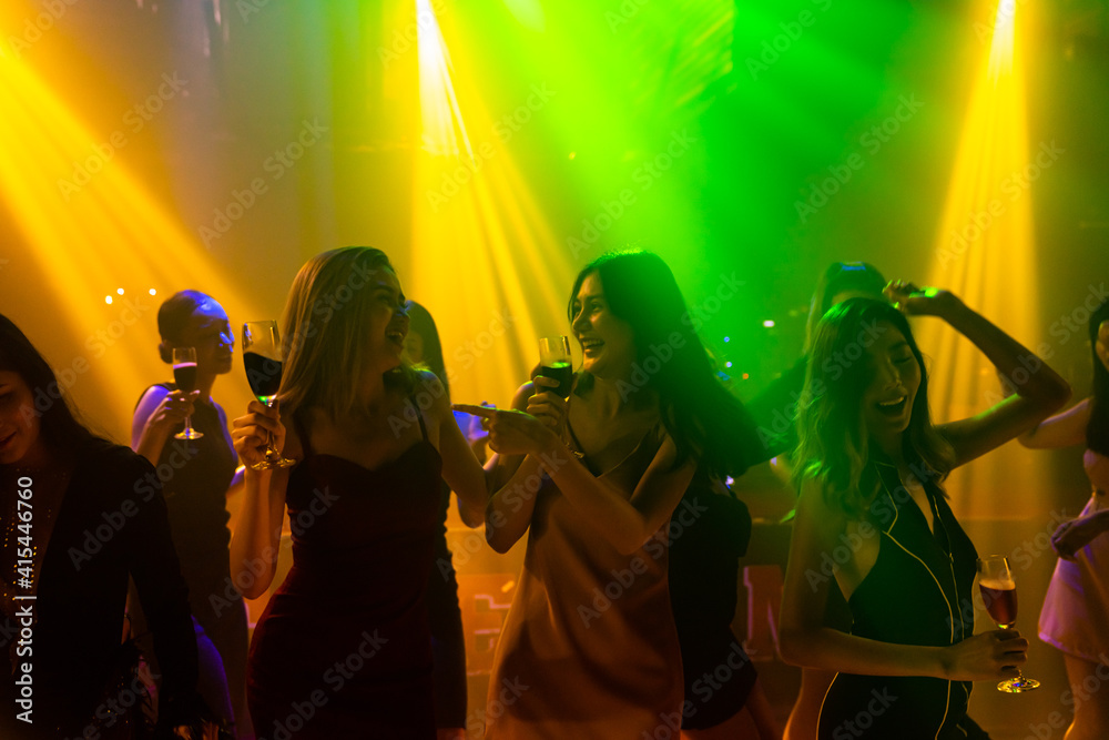 Silhouette image of people dance in disco night club to music from DJ on stage . New year night part