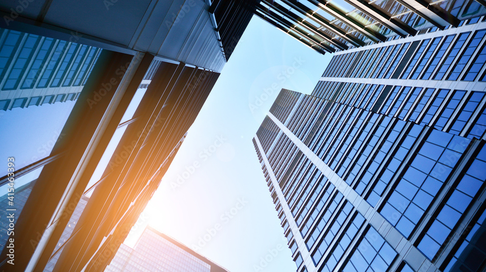 Bottom view of modern skyscrapers in business district against blue sky. Looking up at business buil