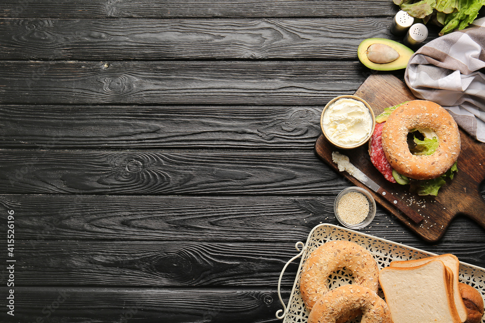 Bagel with tasty cream cheese on wooden background