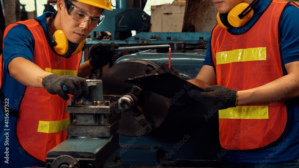 Group of skillful factory workers using machine equipment in workshop . Industry and engineering peo