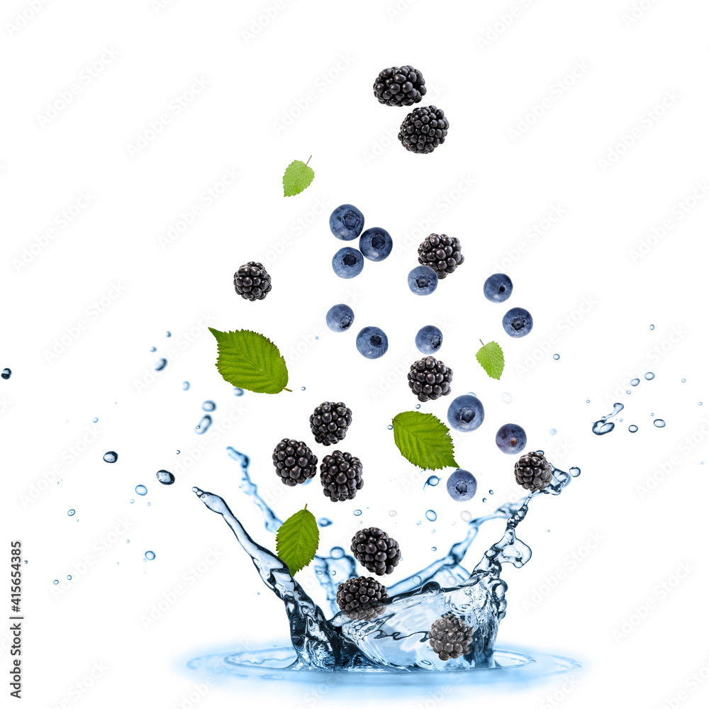 Fresh blueberries and blackberries with mint leaves falling in splashing water isolated on white