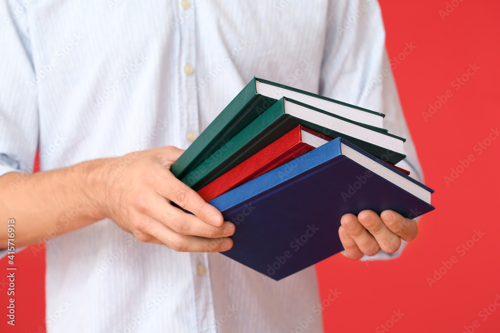 Young man with books on color background, closeup