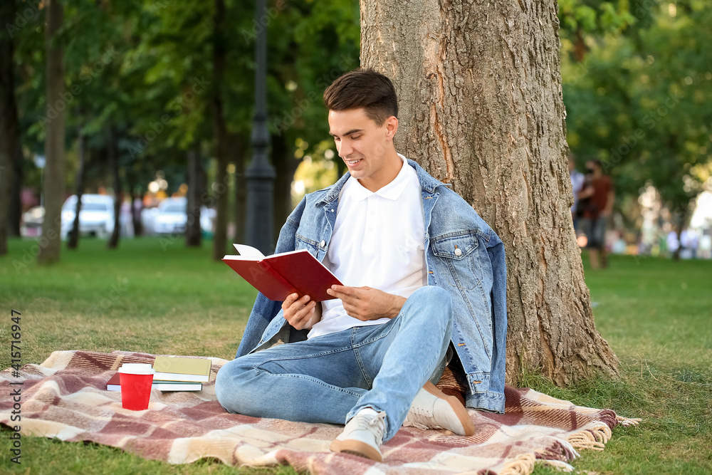 Young man reading book in park