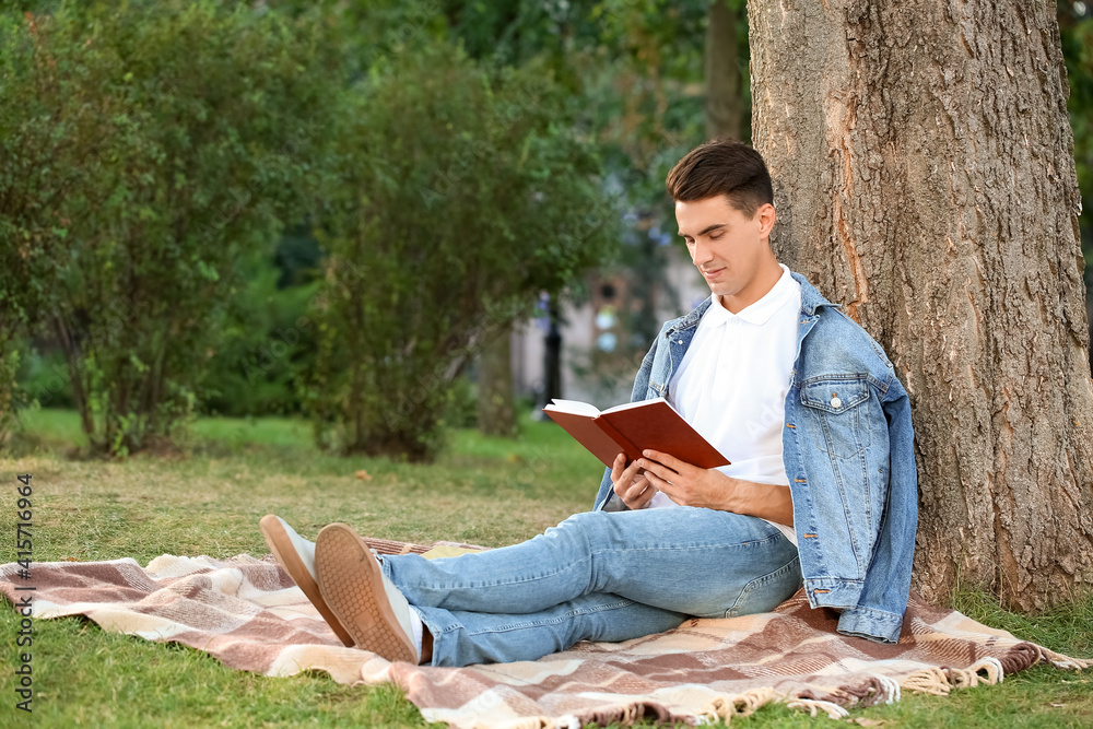 Young man reading book in park