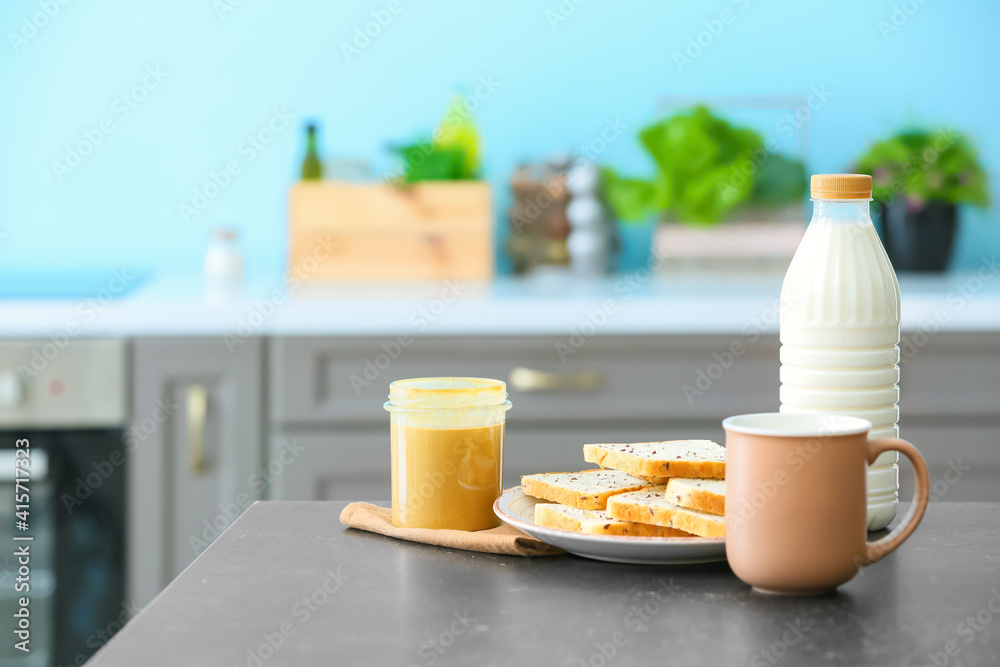 Peanut butter, milk and toasts on table in modern kitchen